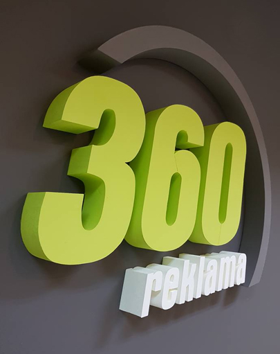 Przestrzenne logo reklama360 w kolorze limonkowym na grafitowej ścianie biura